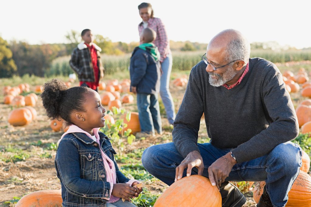 grandfater picking pumkins with his granddaughter